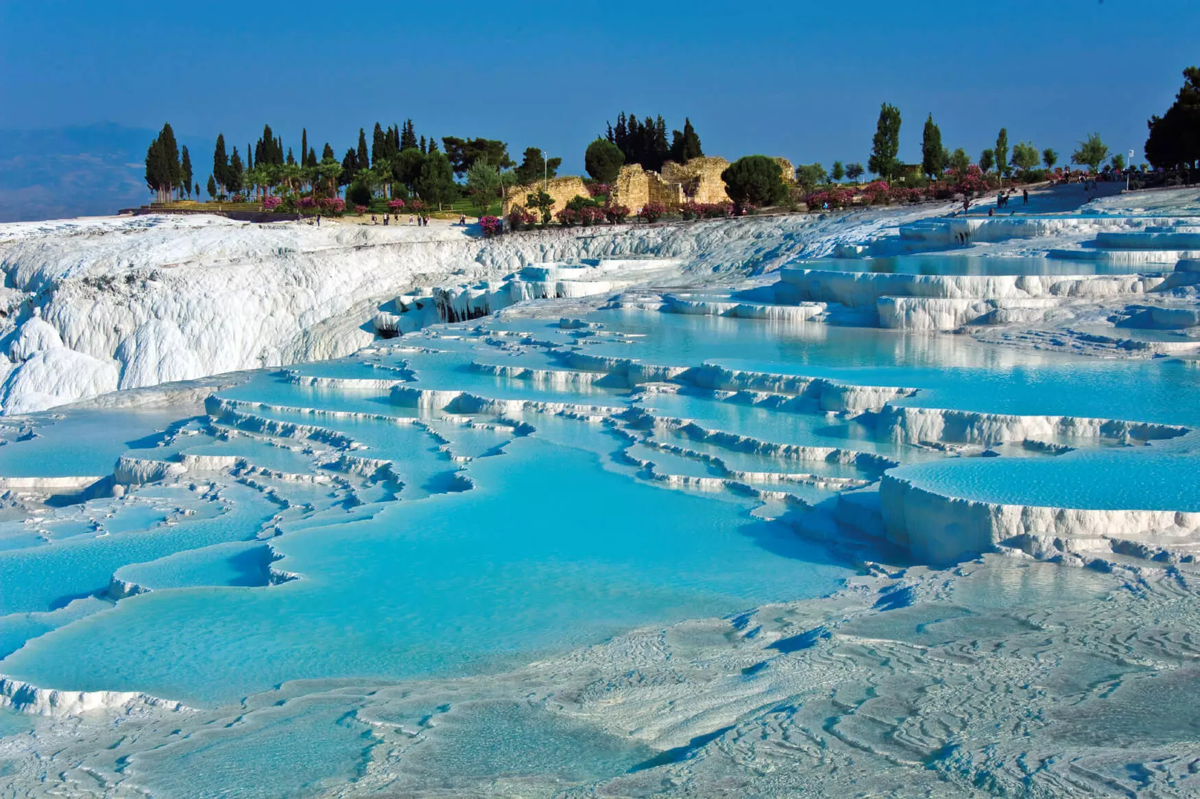 White travertine terraces of Pamukkale in Turkey forming natural pools used as unique filming landscapes.